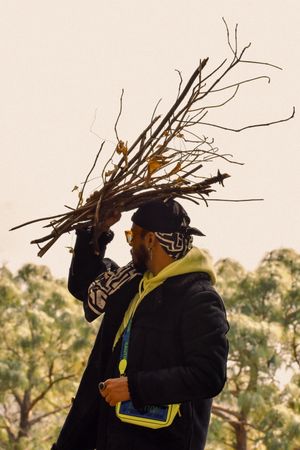 Side view of man holding tree branches for bonfire