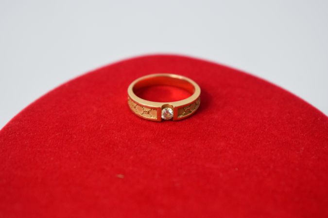 Man's diamond gold ring on red material with copy space