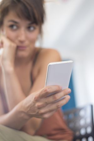 Shy woman blurred in background reading something on phone